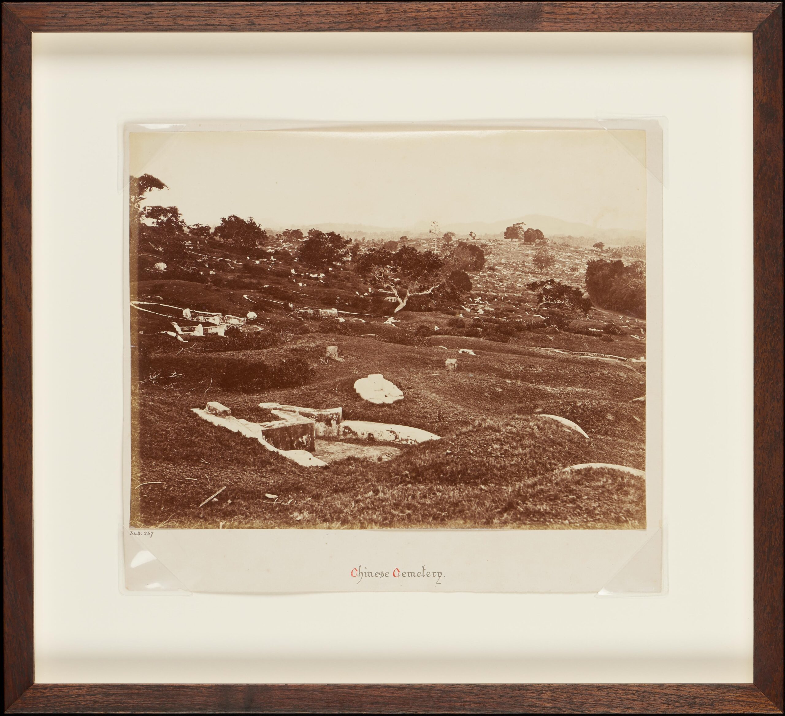 A sepia-toned photograph depicting a hilly cemetery with scattered gravestones, framed and labeled "Chinese Cemetery." The terrain is dotted with trees and shrubs.